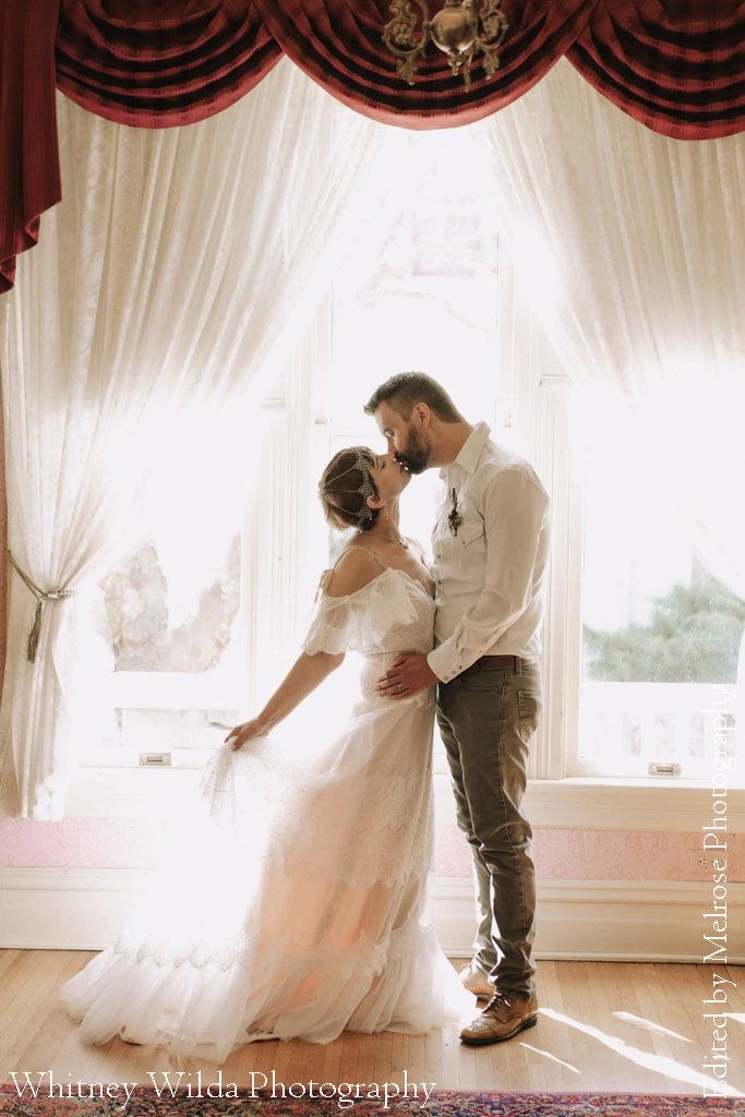 Bride and groom sharing a kiss by the parlor window